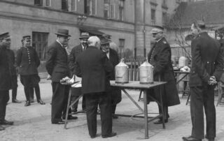 Inżynier Galperin podczas prezentacji swojego wynalazku polegającego na zastosowaniu specjalnego zbiornika do benzyny zabezpieczającego przed wybuchem Źródło: Narodowe Archiwum Cyfrowe, domena publiczna Link: https://www.szukajwarchiwach.gov.pl/jednostka/-/jednostka/5903954/obiekty/390823#opis_obiektu